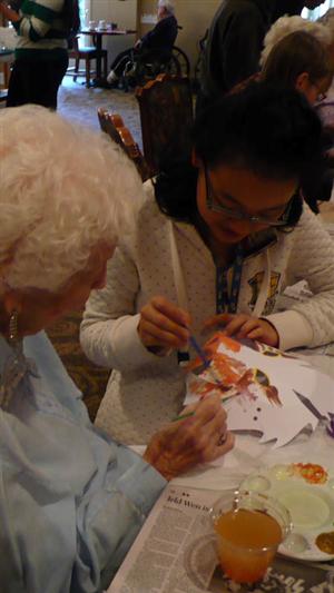 Adeline Xu paints a mask with a resident of Tanner Springs 